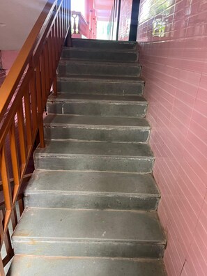 A staircase with wooden handrails and a pink wall. - Abbi S Nest (Calangute)