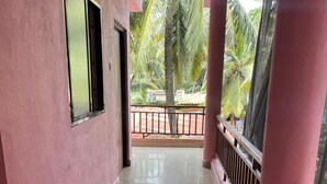 A corridor with pink walls and a balcony with a metal railing. - Abbi S Nest (Calangute)