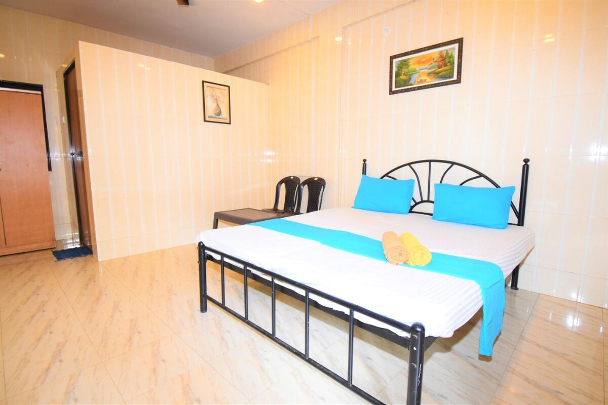 A bedroom with a bed, a nightstand, a chair, and a door.