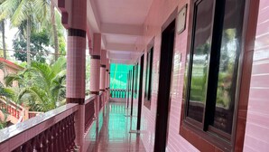 A corridor with pink tiled walls and a marble floor, leading to a balcony with a railing. - Abbi S Nest (Calangute)