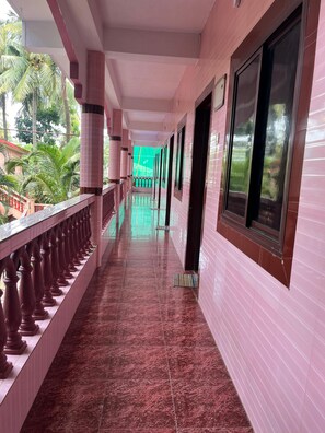 A corridor with pink tiled walls and a marble floor, leading to a balcony with a railing. - Abbi S Nest (Calangute)