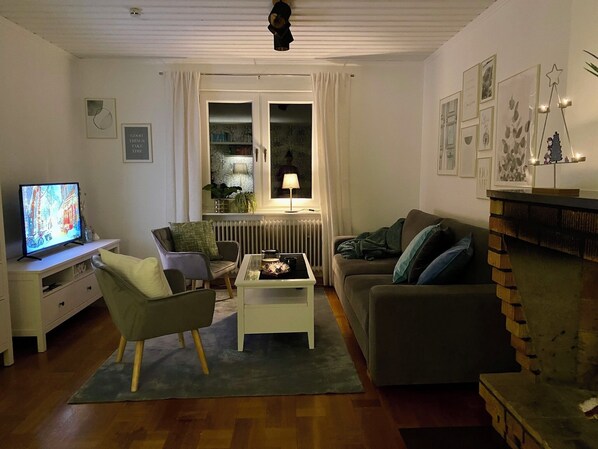 A living room with a television, two armchairs, a coffee table, and a fireplace.