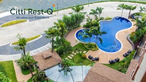 Ein Resort mit Schwimmbad, Palmen und Sitzgelegenheiten im Freien.