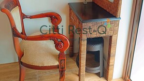 Ein Holzstuhl mit gepolstertem Sitz und Rückenlehne, ein kleiner Tisch mit Spiegel und eine Vase mit Blumen, sowie ein Katzenbaum.