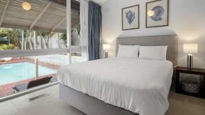 A modern bedroom with a large bed, two bedside lamps, and framed artwork on the wall. - 5-Bed Haven with Pool Minutes From Beaches & Parks (Beaumaris)