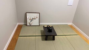 A tatami mat room with a small table, a framed artwork, and a traditional tea set. - Newly Renovated 1br1ba With Asian Style Tea Room (Edmonton)