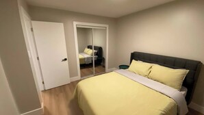 A bedroom with a bed, a door, and a mirror.