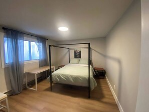 Un dormitorio con cama con dosel, un escritorio y una ventana con cortinas.