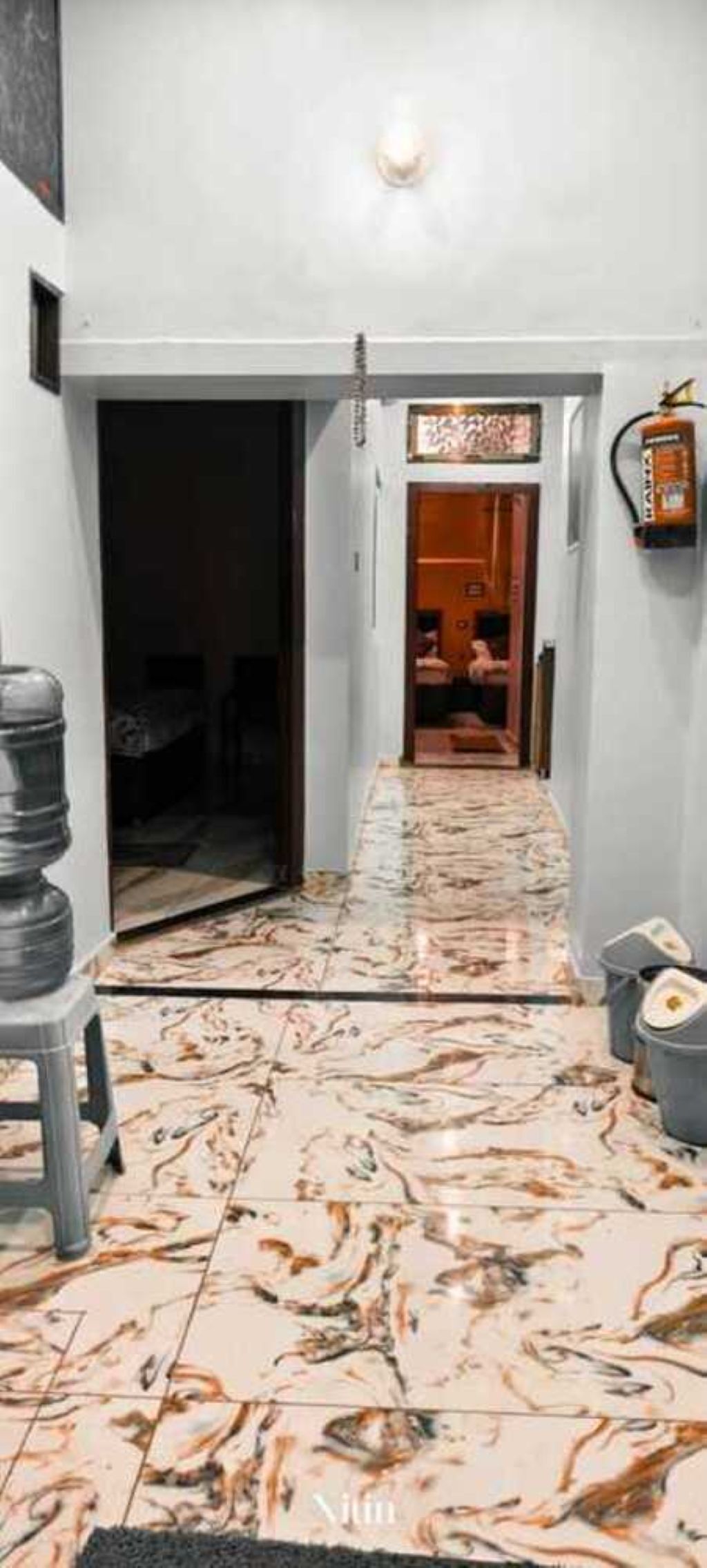 A hallway with a patterned floor leading to a room with a door.