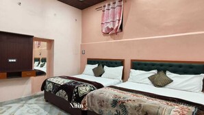 Une chambre avec deux lits, une armoire, un miroir et un rideau suspendu.