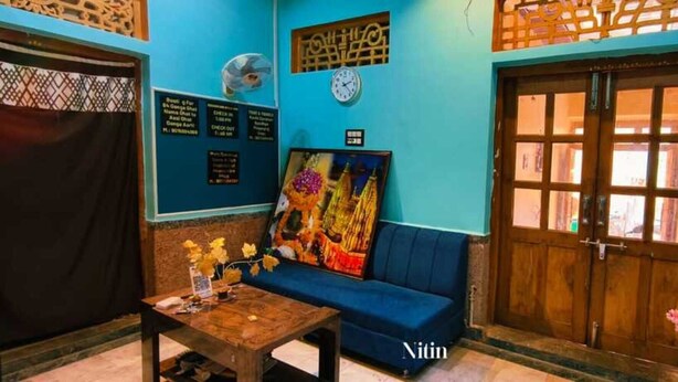 Une pièce avec un canapé bleu, une table en bois ornée d’un vase de fleurs et un tableau accroché au mur.