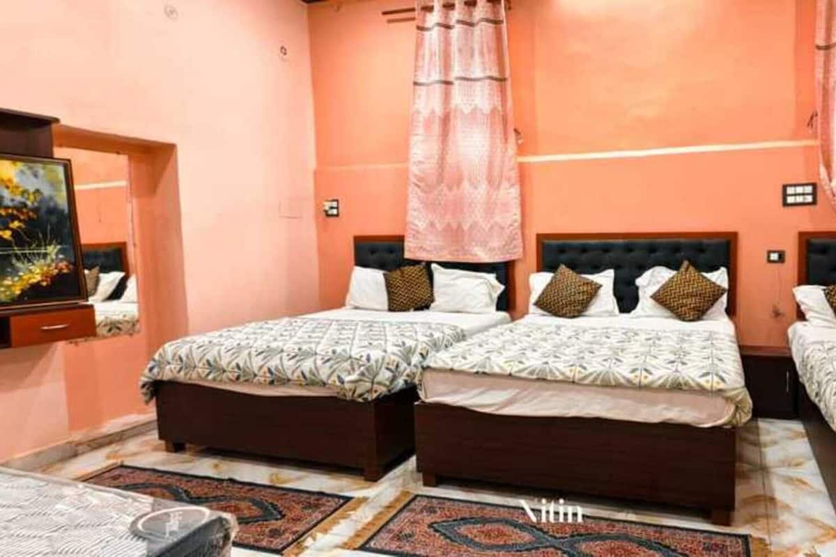 A hotel room with three beds, a large painting on the wall, and a patterned rug.