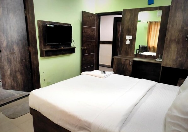 Habitación de hotel con cama, televisión montada en la pared, espejo y armario.