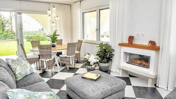 Ein modernes Wohnzimmer mit Schachbrettfußboden, grauem Sofa und Kamin.