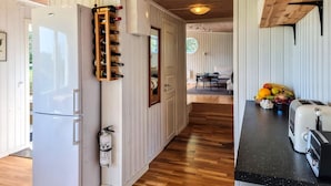 A kitchen with a wooden wine rack, a white refrigerator, a toaster, and a fruit bowl on the counter.
