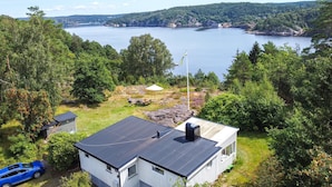 A house with a metal roof, a flag, and a view of a lake surrounded by trees.