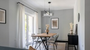 Un salon moderne comprenant un canapé, une table à manger avec des chaises, un meuble noir et un ventilateur de plafond.