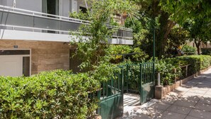 Un immeuble résidentiel doté d’un balcon, d’une porte en bois et d’un portail en métal vert.