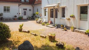 A courtyard with a building, outdoor seating, and potted plants. - Haevn by the Sea, Koje Room (Reußenköge)