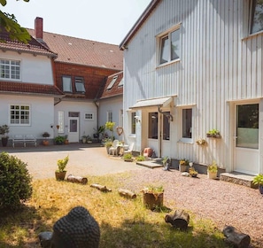 Ein Innenhof mit einem Gebäude, Sitzgelegenheiten im Freien und Blumentöpfen.