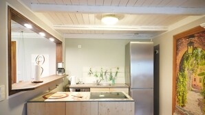 A modern kitchen with wooden cabinetry, a built-in island, a stainless steel refrigerator, and a decorative wall mural. - Haevn by the Sea, Koje Room (Reußenköge)