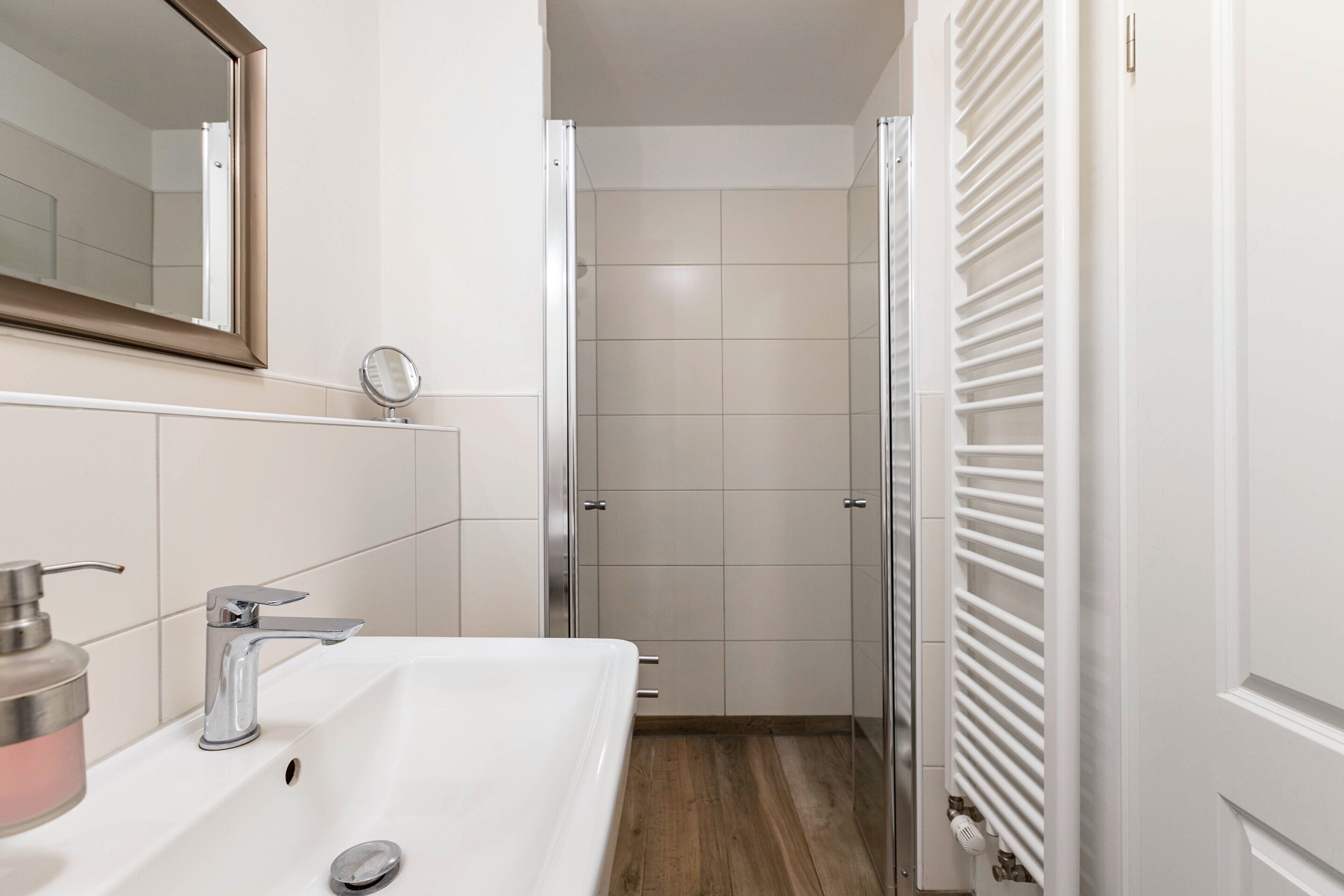 Ein Badezimmer mit einem weißen Waschbecken, Spiegel und Dusche.