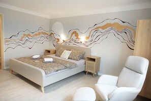 A modern bedroom with a bed, bedside tables, a chair, and a wall mural.