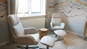 A room with two chairs, a small round table, and a window with curtains. - Haevn by the Sea, Luft Room (Reußenköge)