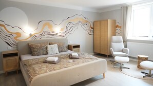 A modern bedroom with a large bed, a chair, a wardrobe, and a window. - Haevn by the Sea, Luft Room (Reußenköge)