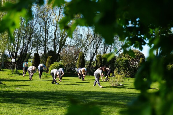 A group of people in a grassy outdoor area with trees and a clear sky.