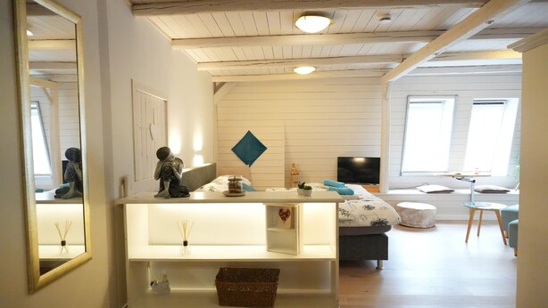 Un salon moderne avec une console blanche, un canapé et un téléviseur.