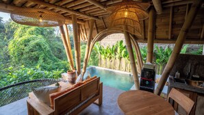 A wooden outdoor seating area with a pool, bamboo ceiling, and lush greenery. - Mahajiva (Abiansemal)