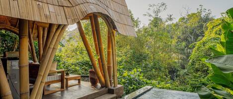 Área de piscina com espreguiçadeiras e estrutura de bambu.