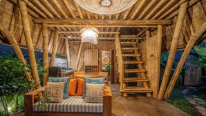 A bamboo-themed interior with a sofa, table, and staircase. - Mahajiva (Abiansemal)