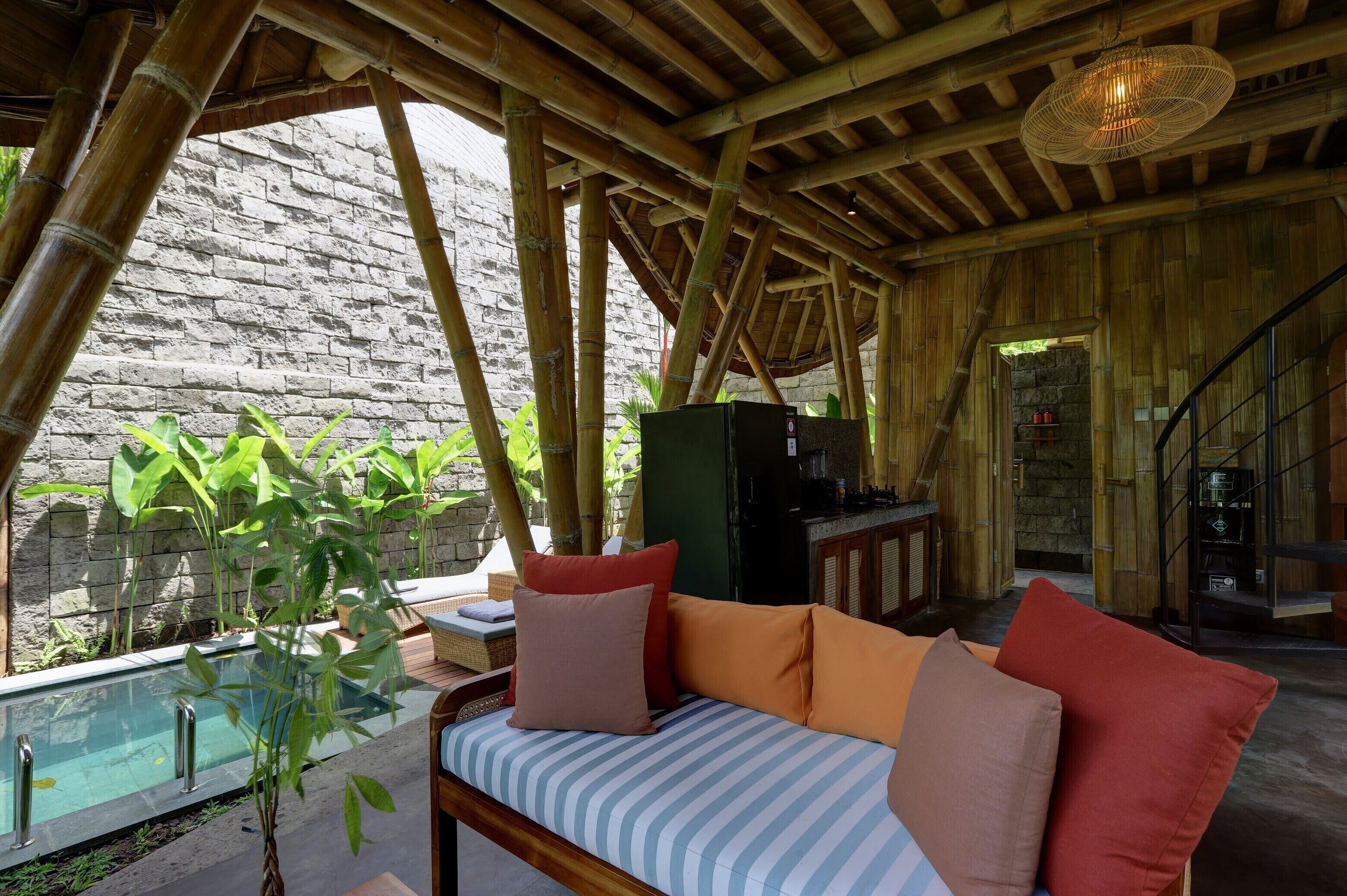 Una habitación con techo de bambú, piscina y sofá con cojines.