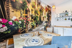 Un restaurant chaleureux avec un mur en pierre rustique, une table en bois agrémentée de sets de table et une variété de plantes en pot.