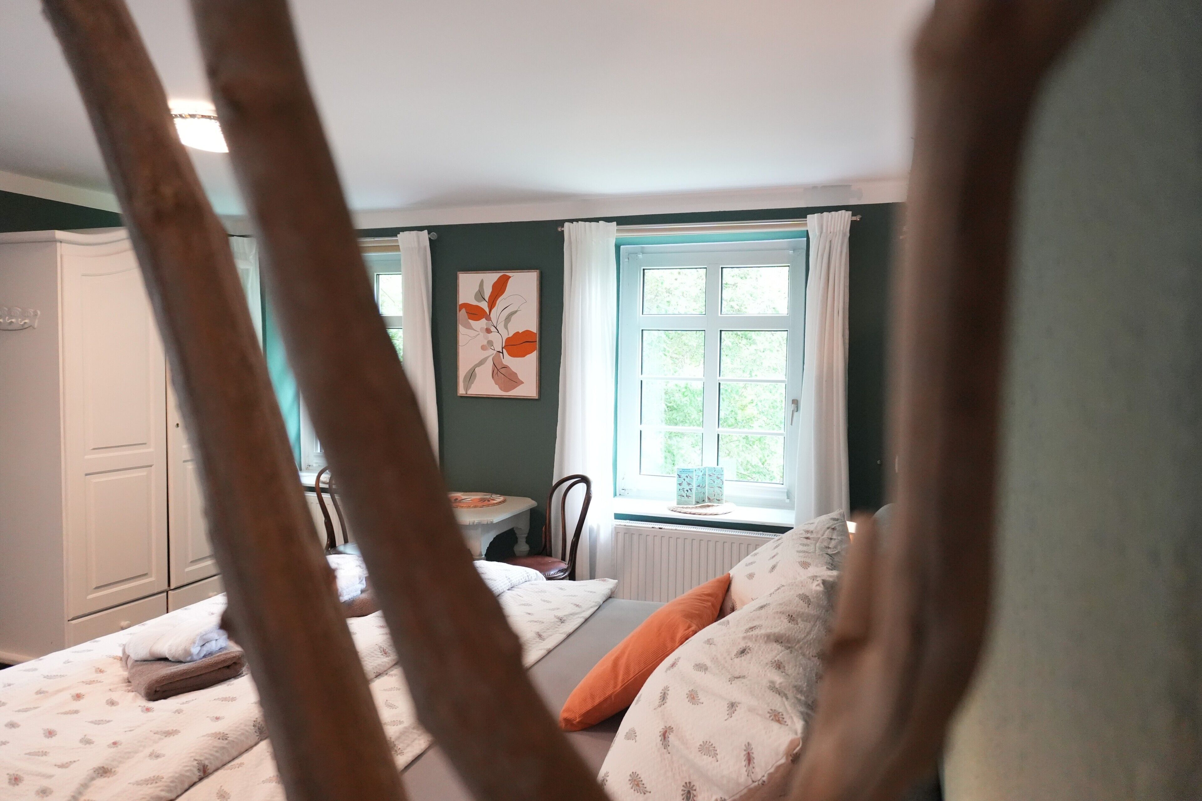 Ein Schlafzimmer mit Bett, Stuhl, Tisch und Fenster.