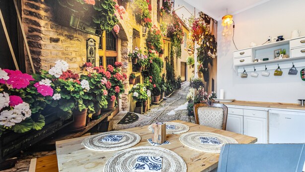 Un restaurante acogedor con una pared de piedra rústica, una mesa de madera con individuales y una variedad de plantas en macetas.