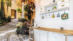 Una cocina con un refrigerador blanco, encimera de madera y utensilios colgando.