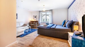 Un dormitorio con cama, mesita de noche, lámpara y vistas al exterior.