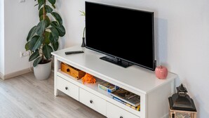 A white entertainment unit with a television, remote, and storage drawers. - Apartment 'Leon, 110 sqm' with Balcony, Wi-Fi and Air Conditioning (Kappel-Grafenhausen)