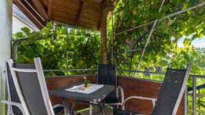 A covered outdoor seating area with a table and chairs, surrounded by lush green foliage. - Apartment 'Leon, 110 sqm' with Balcony, Wi-Fi and Air Conditioning (Kappel-Grafenhausen)