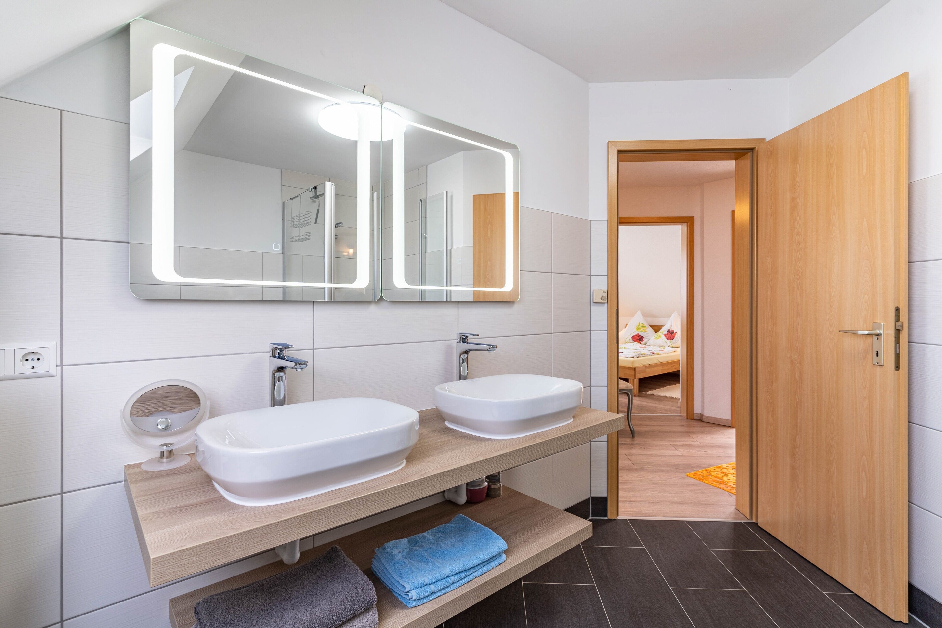 Ein modernes Badezimmer mit zwei Waschbecken, einem großen Spiegel und einer Holzausstattung.