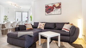 A modern living room with a dark grey sofa, a white coffee table, and a painting of red flowers on the wall. - Apartment 'Leon, 110 sqm' with Balcony, Wi-Fi and Air Conditioning (Kappel-Grafenhausen)