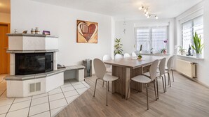 A modern kitchen with a built-in stove, white cabinets, and a dining area with a wooden table and chairs. - Apartment 'Leon, 110 sqm' with Balcony, Wi-Fi and Air Conditioning (Kappel-Grafenhausen)