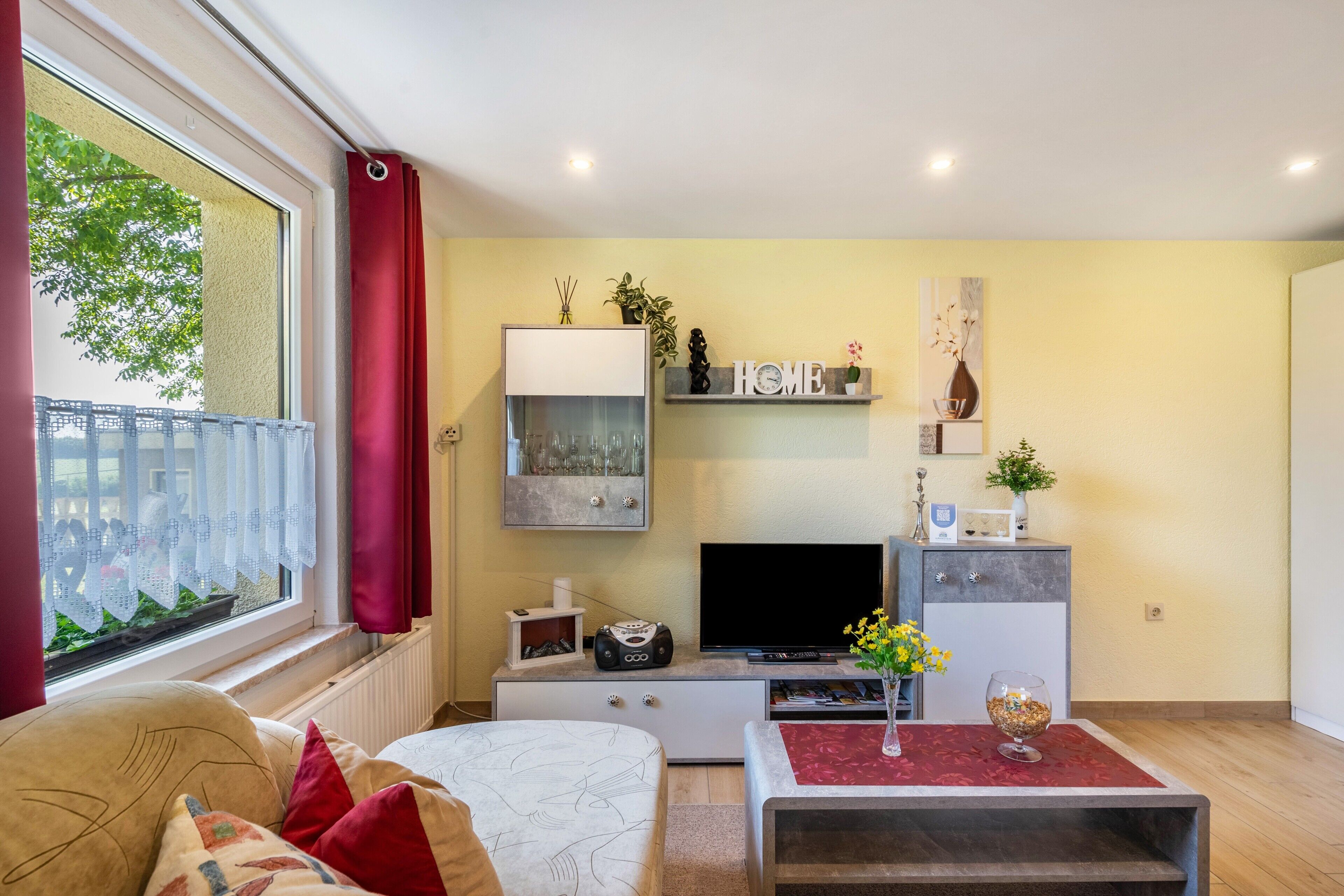 Ein Wohnzimmer mit einer Couch, einem Fernseher und einem kleinen Tisch mit einer Vase.