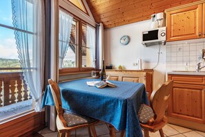 Puisesti sisustettu tila, jossa on ruokapöytä, tuoleja, keittiöalue ja näkymä ikkunasta.