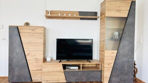 A modern entertainment unit with a flat-screen TV, wooden shelves, and a built-in cabinet. - Apartment 'Fuchsbau' with Mountain View, Private Terrace and Wi-Fi (Vordertheissenegg)