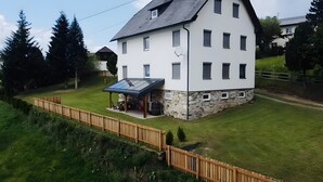 A two-story house with a stone foundation, a covered patio, and a fenced yard. - Apartment 'Fuchsbau' with Mountain View, Private Terrace and Wi-Fi (Vordertheissenegg)