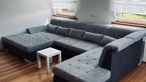 A modern living room with a sectional sofa, a small white table, and a view of greenery outside. - Apartment 'Fuchsbau' with Mountain View, Private Terrace and Wi-Fi (Vordertheissenegg)